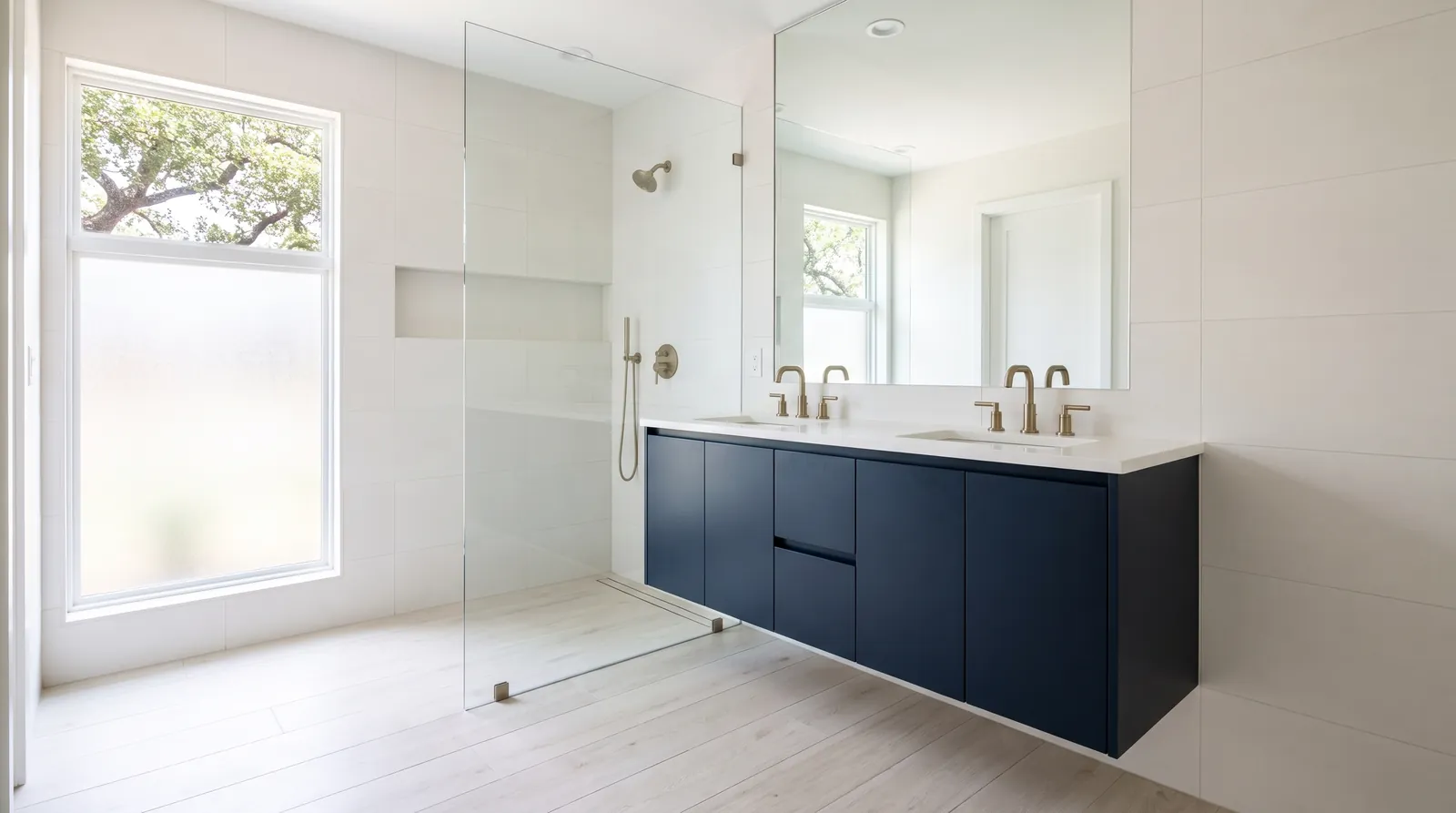 Remodeled primary bathroom with a navy floating vanity and a glass shower panel