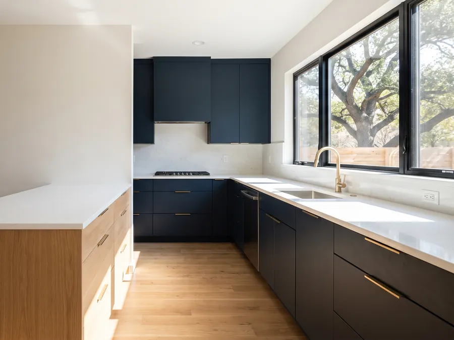 Remodeled kitchen with navy cabinets, a white oak island, and a window onto a live oak