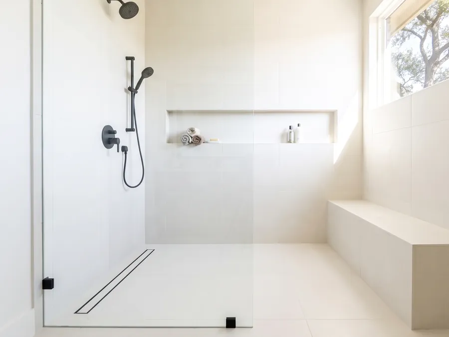 Curbless walk-in shower with a linear drain, a tiled bench, and a long niche